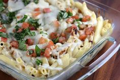 a casserole dish with tomatoes, cheese and herbs in it on a wooden table