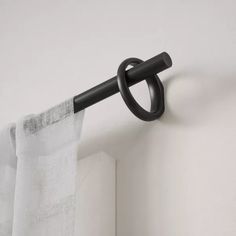 the curtain is hanging on the wall with an open black ring attached to it's rod