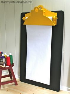 a black and yellow easel sitting in front of a white paper towel on top of a wooden table