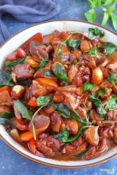 a bowl filled with meat and spinach on top of a table next to a blue cloth