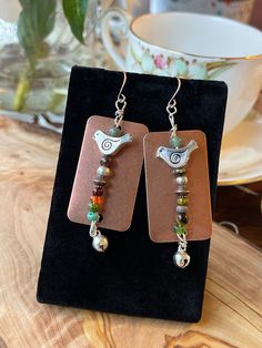 Copper and mixed metals. Mixed color beads with birds and bells. Length 2 inches and just under 1 inch wide Unique Silver Metal Beaded Earrings, Unique Copper Beaded Earrings Nickel Free, Bohemian Beaded Copper Earrings, Beaded Bronze Metal Earrings, Bronze Beaded Metal Earrings, Multicolor Beaded Copper Jewelry, Unique Copper Jewelry With Dangling Beads, Unique Nickel-free Copper Beaded Earrings, Bohemian Rust-colored Copper Jewelry