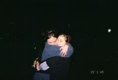 two people hugging each other in the dark