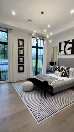 a modern bedroom with white and black decor on the walls, wood flooring and large windows