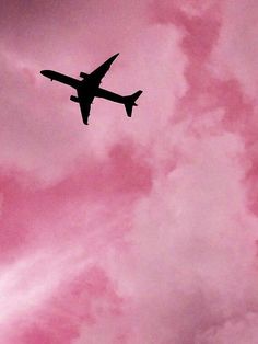 an airplane is flying in the sky with pink clouds