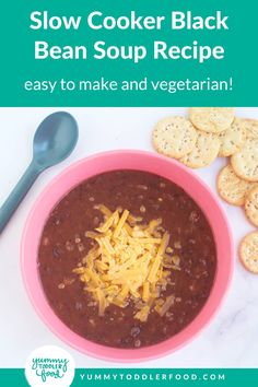 a pink bowl filled with beans and cheese next to crackers on a white table