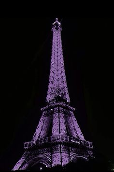 the eiffel tower lit up at night in purple light, with people standing on top