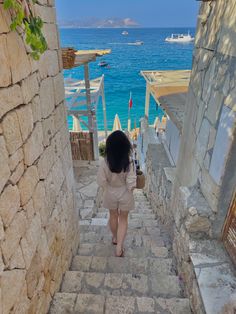 a woman walking up some steps towards the ocean