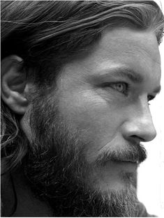 a close up of a person with a long hair and beard wearing an earring