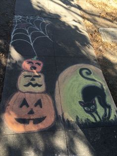 two chalk drawings of cats and pumpkins on the sidewalk