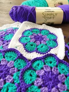 purple and green crocheted afghans with yarn on the floor next to them