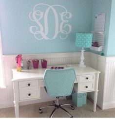 a white desk topped with a blue chair under a monogrammed wall decal