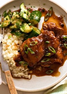 a white plate topped with rice and meat covered in gravy next to broccoli