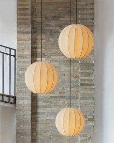 three lamps hanging from the side of a brick wall in a living room next to a staircase