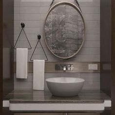 a white bowl sink sitting under a round mirror