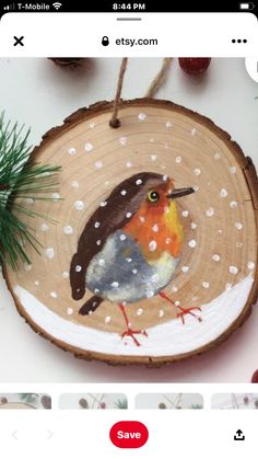 an image of a bird painted on a wood slice ornament with pine needles