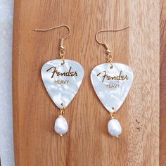 a pair of earrings with the words fenderer heavy and pearl beads hanging from them