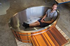 a man sitting in a wooden and metal tub