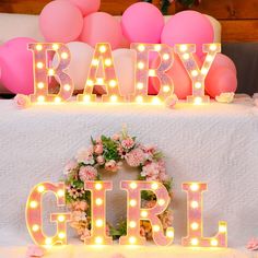 a table topped with pink and white balloons next to a sign that says baby girl