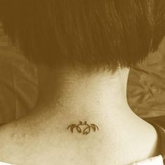 a woman's back neck with a small tattoo on the upper part of her neck