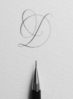 a fountain pen drawing the letter e on white paper with an inking pen in it