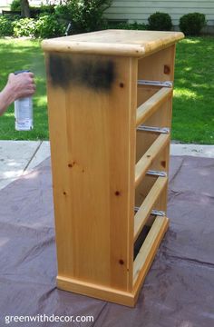 a wooden cabinet with metal bars on the top and bottom, in front of a house