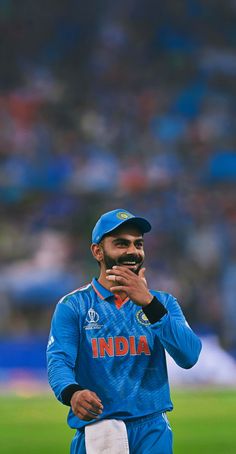 a man in blue uniform standing on top of a field with his hand to his mouth