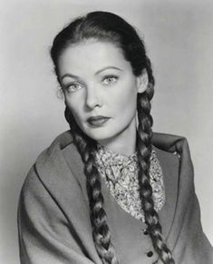 an old black and white photo of a woman with braids in her hair wearing a coat