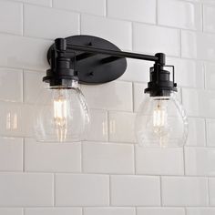 three light fixtures mounted on a white tile wall in a bathroom with black fittings