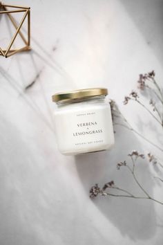 a jar of lemongrass sitting on top of a table next to some dried flowers