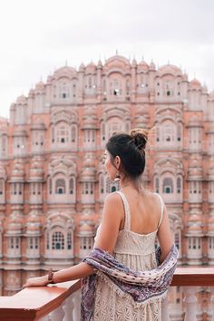 a woman standing on top of a balcony next to a tall building