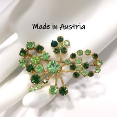 *Description: This is a beautiful green rhinestone brooch, made in Austria, from the 1950s. Some of the light green rhinestones are Vaseline or Uranium Glass. Please see last photo for details. The rhinestones are in two shades of green; peridot green and emerald green, on a gold tone background. All of the Austrian brooches have exquisite rhinestones. This would be a great addition to your vintage jewelry collection or make a great vintage gift! *Approximate Measurements: Length - 1 1/2 Inches, Antique Green Brooch For Evening, Vintage Green Evening Brooch, Retro Green Brooch Jewelry, Vintage Green Diamond Brooches, Formal Earrings, Vintage Green Rhinestone Brooch, Vintage Christmas Gifts, Book Pieces, Floral Brooch