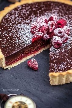 a chocolate tart with raspberries and powdered sugar on top, ready to be eaten