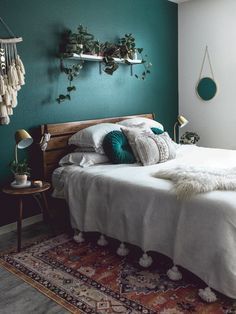 a bedroom with green walls, white bedding and plants on the wall above it