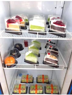 an open refrigerator filled with different types of cakes and desserts in plastic containers on shelves