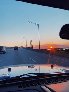 the sun is setting on an interstate highway as traffic passes by in front of them