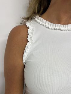 Your go to white top is here!  White ribbed knit fabric that is super stretchy shapes this classic tank style top with ruffle detailing at the shoulder and neckline. This top is fitted making it the great option for tucking into skirts, shorts or pants, it is the perfect base for layering... we can't wait to see how yo White Fitted Top With Ruffles, Chic White Stretch Tank Top, Spring Ruffled Solid Color Tank Top, Summer Ribbed Elastane Tops, Ruffled Tank Top For Spring, Chic White Ribbed Tank Top, White Fitted Tank Top With Ruffled Straps, White Trendy Tops With Ruffled Straps, White Trendy Top With Ruffled Straps