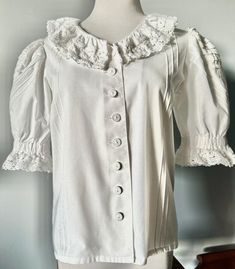 Gorgeous Romantic White DIRNDL TRACHTEN BLOUSE with 2" CROCHET LACE around neckline and sleeves, the Puff Sleeves are beautifully designed with Pleats in 2 different directions, also vertical pleats in the front. the buttons are oldfashioned Linen Buttons, 1 reserve button. Material 50/50 Cotton/Poly Size 38 = US Size 8 actual measurements are: Bust and Waist 38" Length 22" VINTAGE, in excellent condition White Dirndl, Crochet Neckline, Sleeve Ruffles, Blouse White, 50 50, Crochet Lace, Puff Sleeves, Shoulder Pads, Womens Clothing Tops