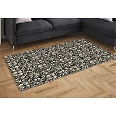 a black and white area rug on a wooden floor in front of a gray couch