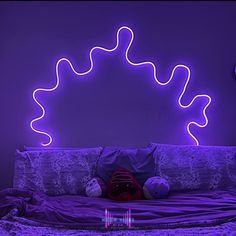 a bed with purple lights on the headboard, and a teddy bear laying on it