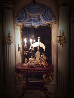 an ornate table with candles on it in front of a mirror