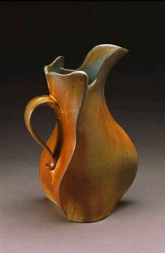 a brown and yellow vase with a heart shaped handle