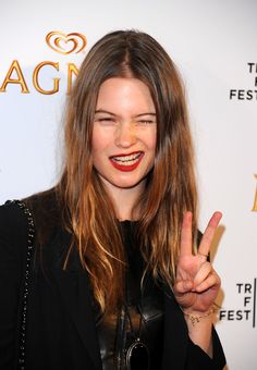 a woman giving the peace sign with her hand and wearing a black leather jacket at an event