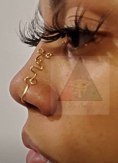 a woman's nose with the word love written on it and gold chains attached to her nose