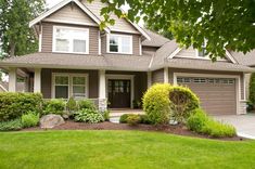 a large house with lots of trees and bushes in front of the garage door is surrounded by lush green grass