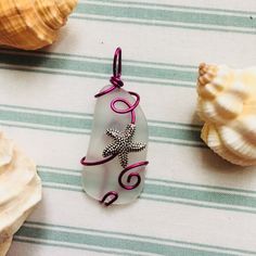 Silver Coated Starfish Charm Wrapped Around A Piece Of Sea Glass Using Magenta Colored Artisan Wire. #Style #Gemstone #Rock #Crystal #Trendy #Handmade #Gift #Her #Gems #Nature #Natural #Stone #Precious #Semiprecious #Statement #Metal #Chakra #Artisan #Chain #Indie #Forest #Intuition #Pride #Color #Luck #Love #Goth #Dainty #Witch #Magic #Beach #Glass #Sea #Fairy #Spring #Summer #Minimalist #Large #Boho #Winter #Fall Silver Wire Wrapped Ocean-themed Jewelry, Silver Wire Wrapped Ocean-inspired Jewelry, Silver Ocean-inspired Wire Wrapped Jewelry, Ocean-inspired Silver Star Jewelry, Ocean-inspired Star Shaped Silver Jewelry, Shell Projects, Sea Fairy, Seaglass Jewelry, Ocean Collection