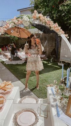 a woman standing in front of a table with plates and an umbrella over her head