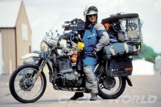 a man is sitting on a motorcycle with luggage strapped to it's back and wearing a helmet