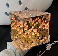 a clear box filled with orange flowers on top of a black table next to a white teddy bear