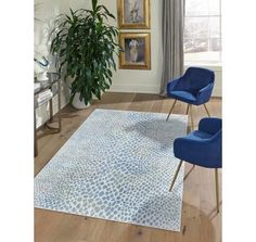 a living room area with blue chairs and a rug on the floor next to a potted plant