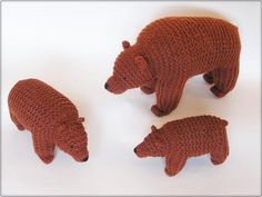 three crocheted bears standing next to each other on a white surface with one bear facing the camera